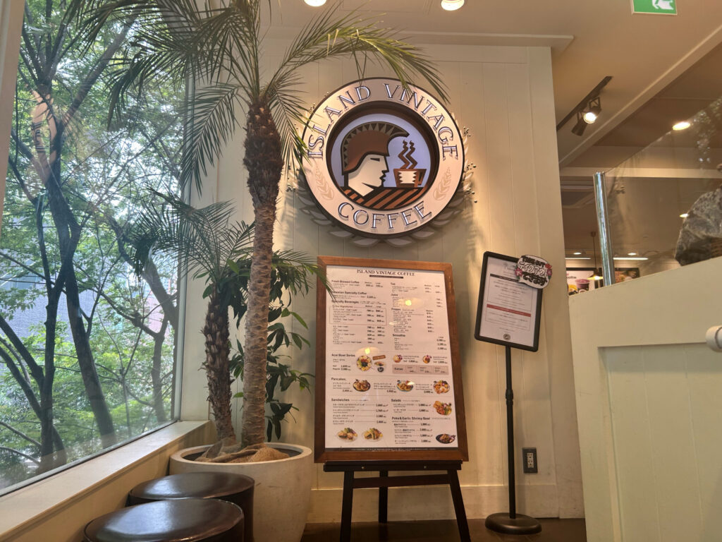 表参道アイランドヴィンテージコーヒーの店内。ロゴとメニュー看板、観葉植物が並ぶエントランス