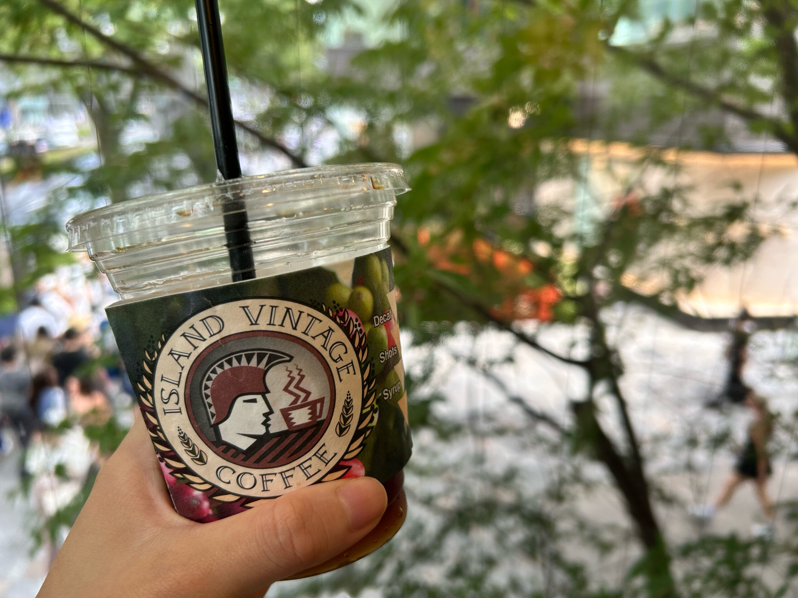 アイランドヴィンテージコーヒーのカップを持つ手と緑の背景